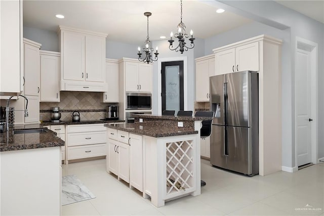 kitchen featuring backsplash, sink, appliances with stainless steel finishes, decorative light fixtures, and a kitchen island