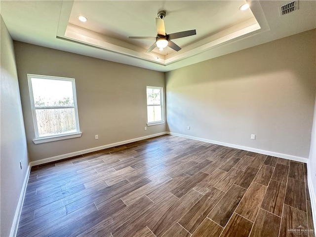 spare room featuring dark hardwood / wood-style floors, a raised ceiling, and ceiling fan