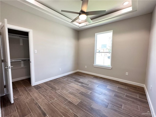 spare room featuring dark hardwood / wood-style floors, ceiling fan, and a tray ceiling