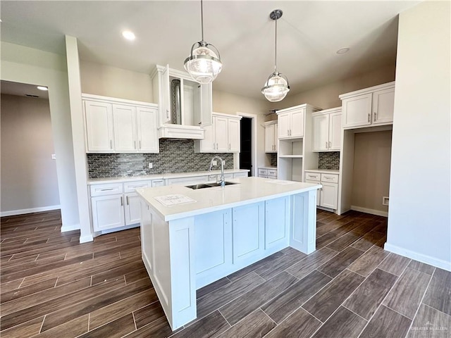 kitchen featuring sink, backsplash, pendant lighting, a center island with sink, and white cabinets