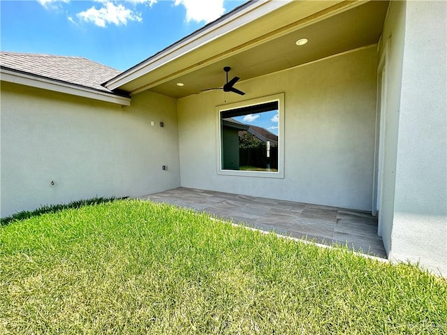 entrance to property with a lawn, ceiling fan, and a patio area