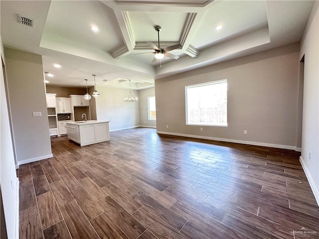 unfurnished living room featuring beam ceiling, ceiling fan with notable chandelier, dark hardwood / wood-style floors, and sink