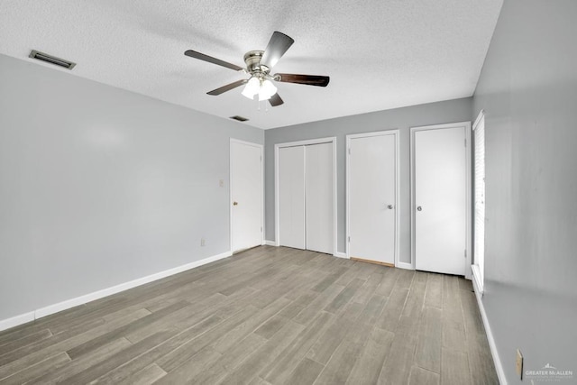 704 Kerry Ln, Mcallen, TX 78504 - unfurnished bedroom featuring multiple closets, a textured ceiling, wood finished floors, and baseboards