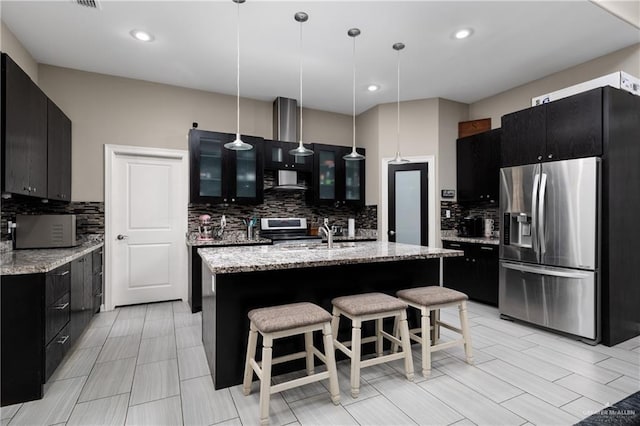 201 White Oak Dr, Los Fresnos, TX 78566 - kitchen with appliances with stainless steel finishes, dark cabinets, decorative backsplash, glass insert cabinets, and decorative light fixtures