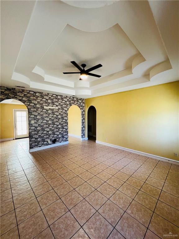 8200 Tierra Linda Ln, Mission, TX 78574 - unfurnished room featuring a tray ceiling, arched walkways, a ceiling fan, and light tile patterned floors
