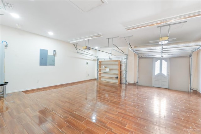 garage featuring visible vents, baseboards, electric panel, and a garage door opener