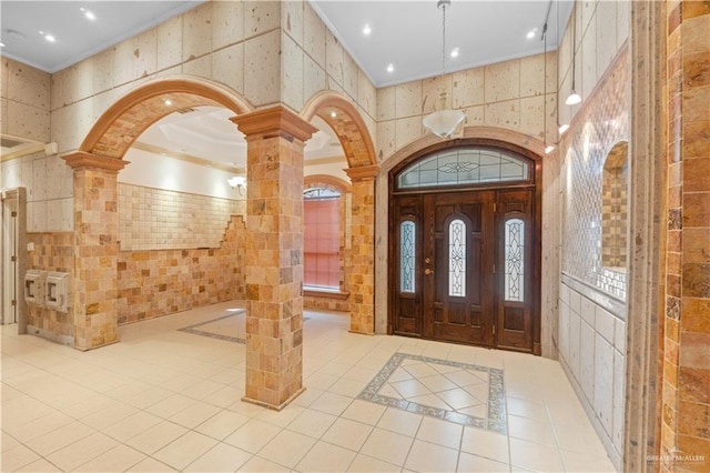 entrance foyer with ornamental molding, recessed lighting, tile patterned flooring, and ornate columns