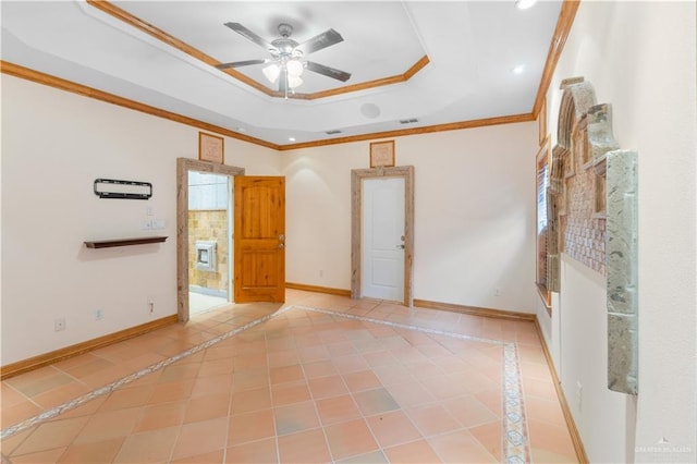 tiled empty room featuring ornamental molding, a raised ceiling, a ceiling fan, and baseboards