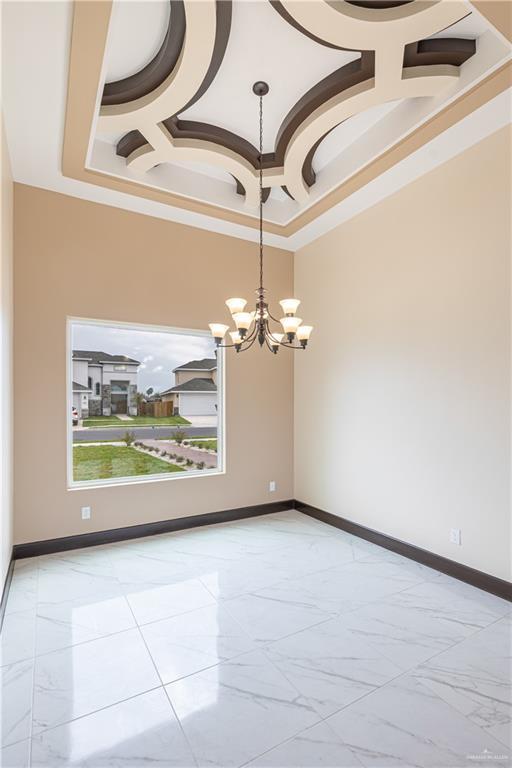 3812 Santa Fe St, Edinburg, TX 78542 - unfurnished room with a chandelier, light marble finish floors, baseboards, a tray ceiling, and crown molding