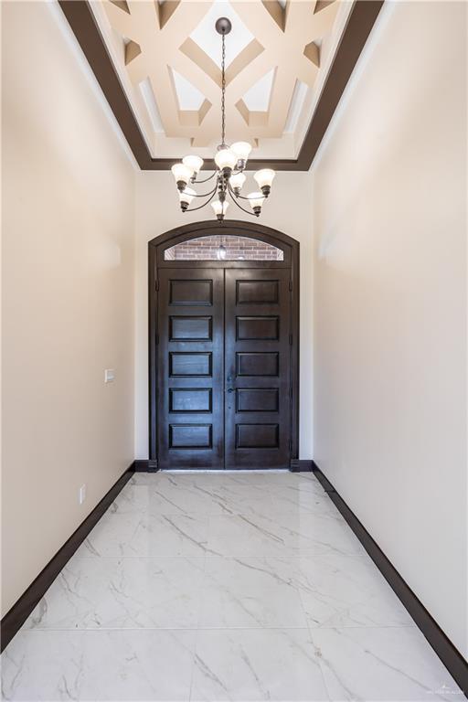 3812 Santa Fe St, Edinburg, TX 78542 - entrance foyer featuring a chandelier, baseboards, coffered ceiling, light marble finish floors, and a high ceiling