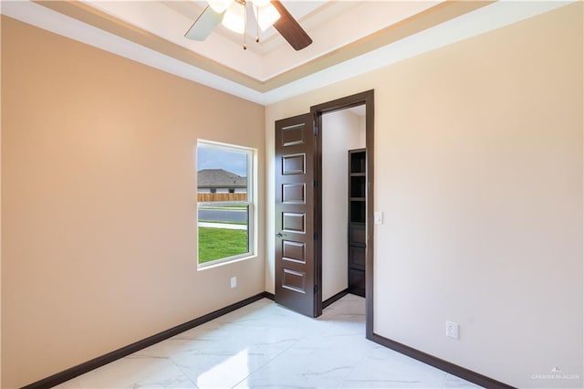 3812 Santa Fe St, Edinburg, TX 78542 - spare room with light marble finish flooring, baseboards, a tray ceiling, and a ceiling fan