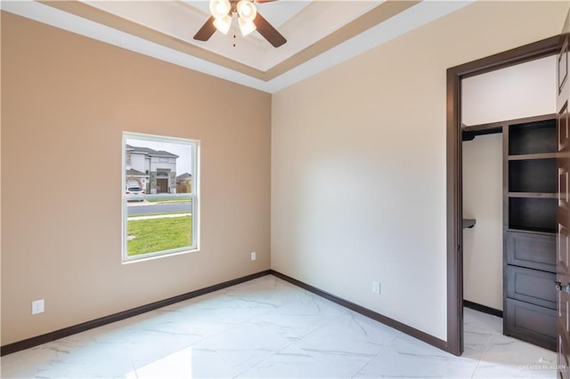 3812 Santa Fe St, Edinburg, TX 78542 - empty room featuring light marble finish floors, a ceiling fan, baseboards, and a tray ceiling