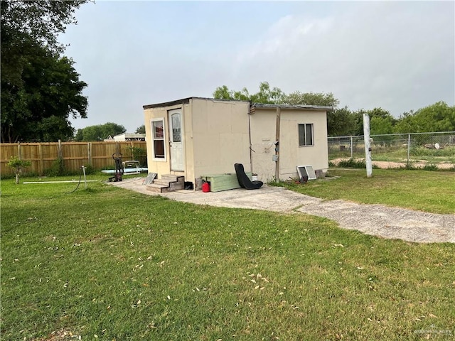 rear view of property with a lawn and an outdoor structure