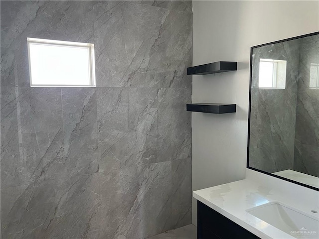 bathroom with a tile shower and vanity