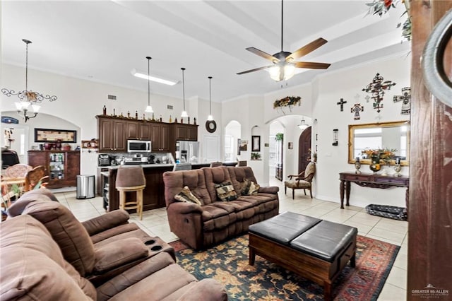 living room with ceiling fan with notable chandelier, light tile patterned floors, ornamental molding, and a towering ceiling