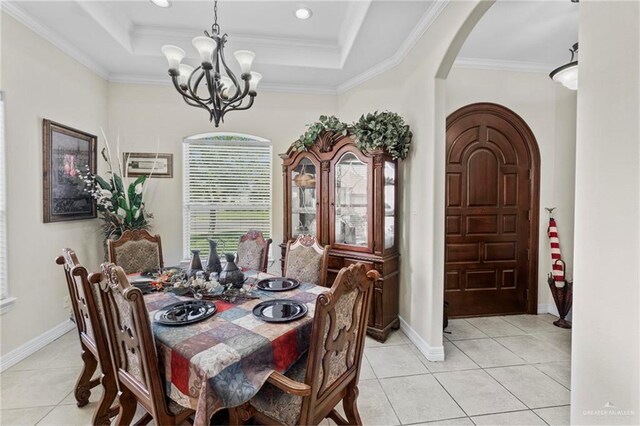 dining area featuring a chandelier, a tray ceiling, crown molding, and light tile patterned flooring