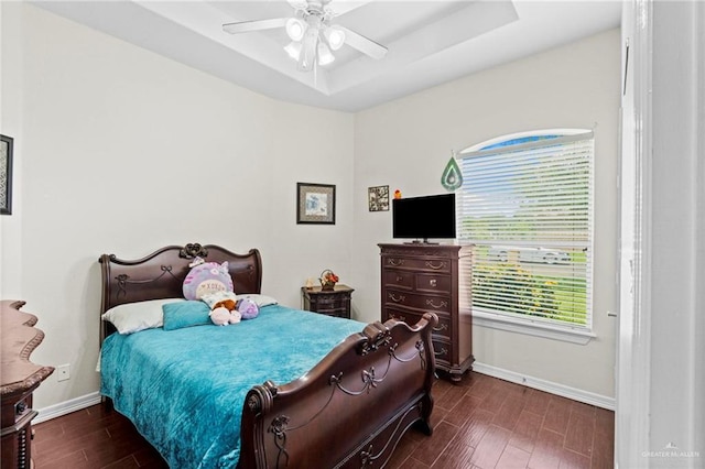 bedroom with a raised ceiling, ceiling fan, and dark wood-type flooring