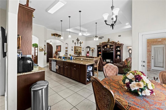 kitchen with stainless steel dishwasher, a tray ceiling, dark brown cabinets, a kitchen island, and ceiling fan with notable chandelier