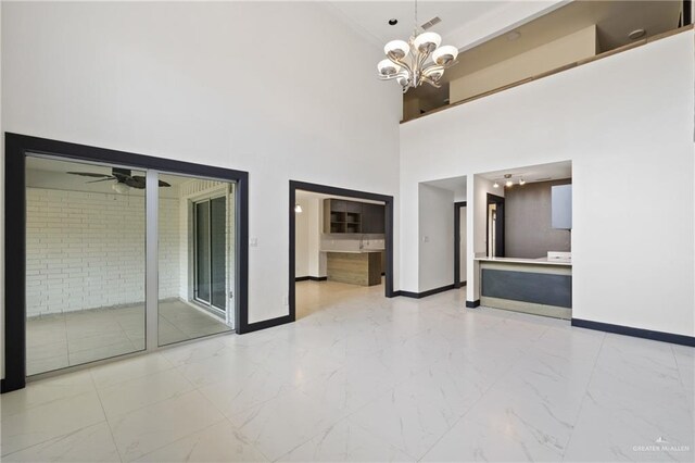 2018 Sabinal St, Mission, TX 78572 - spare room featuring baseboards, light marble finish flooring, a ceiling fan, a chandelier, and a high ceiling