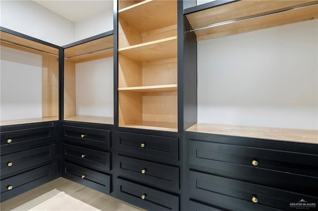 walk in closet with light wood finished floors