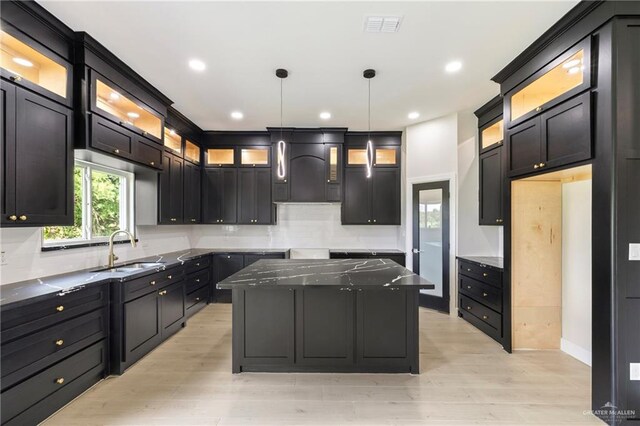 kitchen featuring a sink, light wood-style flooring, tasteful backsplash, and visible vents