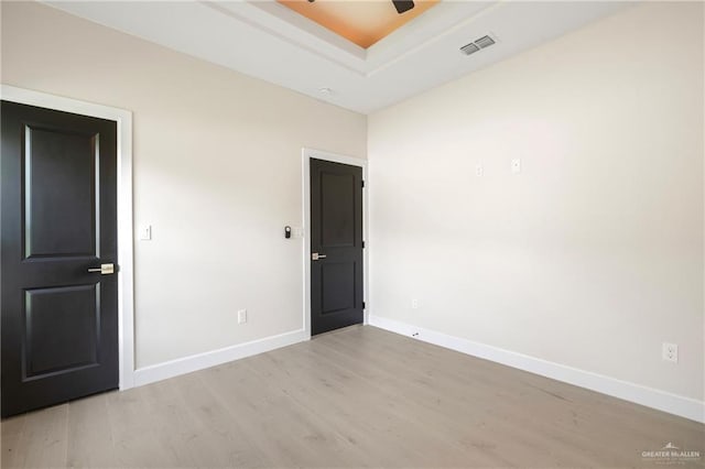 unfurnished room featuring light wood-type flooring, visible vents, baseboards, and a ceiling fan