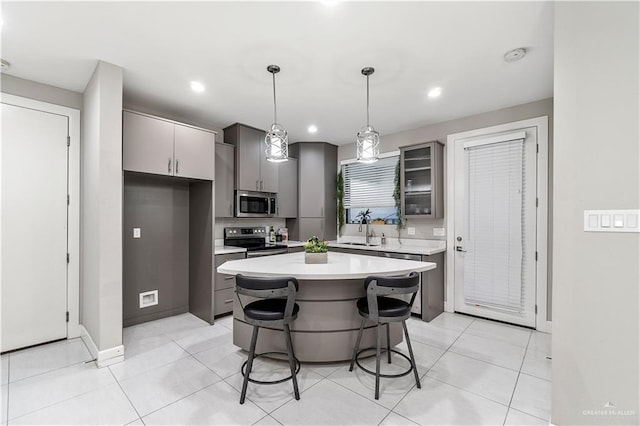 kitchen featuring sink, stainless steel appliances, a kitchen breakfast bar, pendant lighting, and a kitchen island