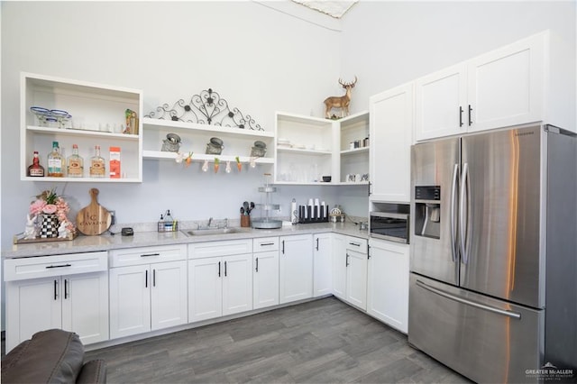 kitchen with dark wood-type flooring, white cabinets, sink, appliances with stainless steel finishes, and light stone counters