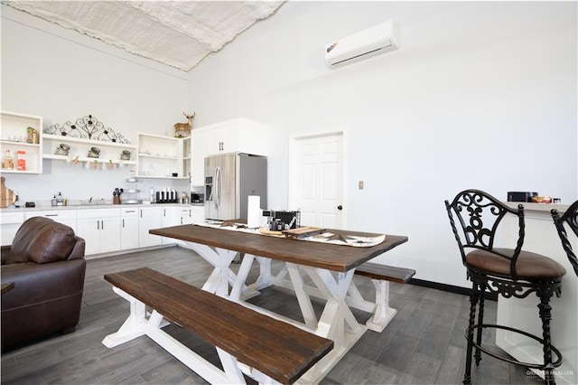 dining room featuring dark hardwood / wood-style floors, an AC wall unit, and a high ceiling