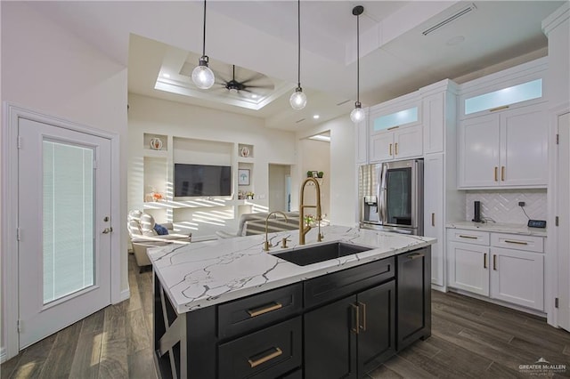 kitchen with pendant lighting, sink, white cabinetry, a center island with sink, and a raised ceiling