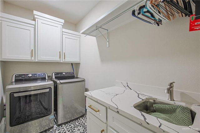 clothes washing area with cabinets, washer and clothes dryer, and sink