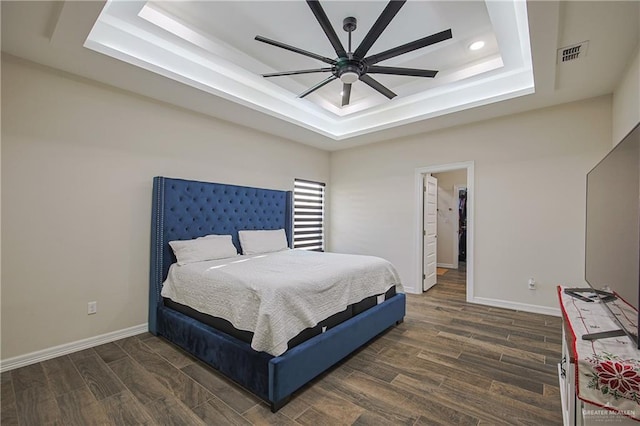 bedroom with dark wood-type flooring, ceiling fan, and a raised ceiling