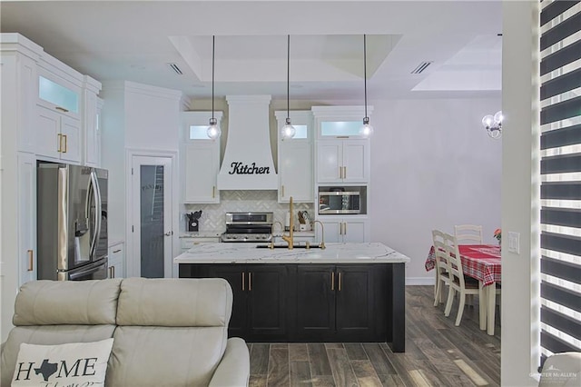 kitchen with pendant lighting, a kitchen island with sink, white cabinetry, stainless steel appliances, and custom exhaust hood