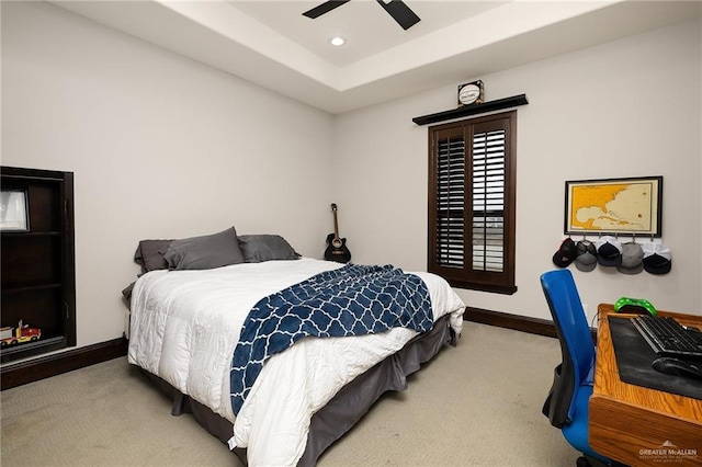 carpeted bedroom with a raised ceiling and ceiling fan