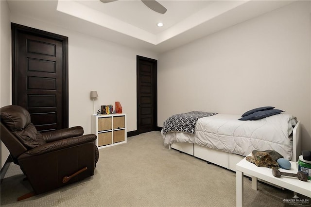 bedroom with a tray ceiling, ceiling fan, and light carpet