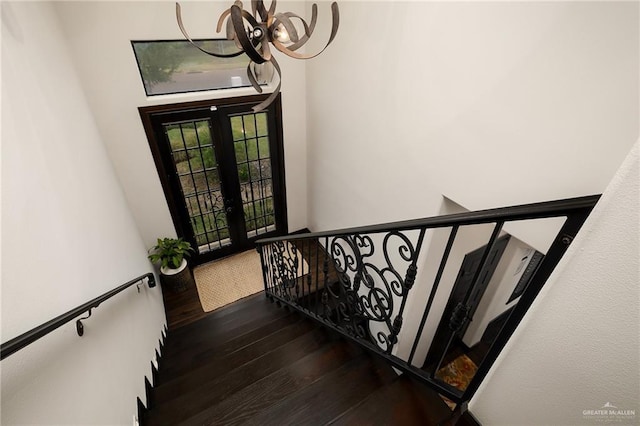 staircase featuring hardwood / wood-style floors, a chandelier, and french doors