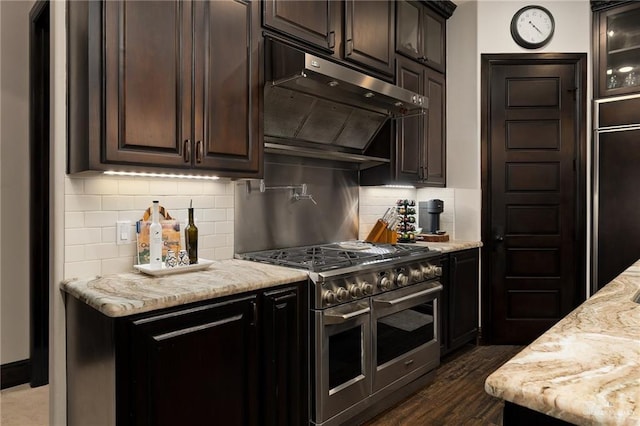 kitchen with premium appliances, light stone counters, dark wood-type flooring, and tasteful backsplash