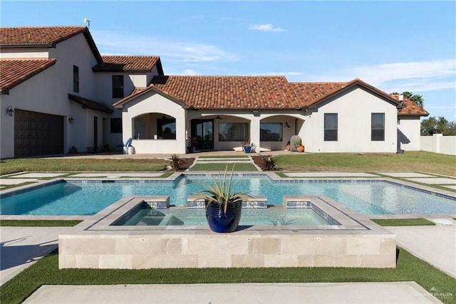 rear view of property with an in ground hot tub, a yard, pool water feature, and a garage