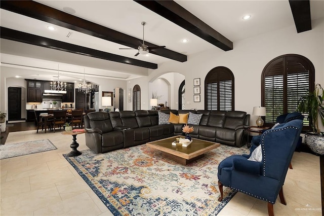 tiled living room featuring beam ceiling and ceiling fan with notable chandelier