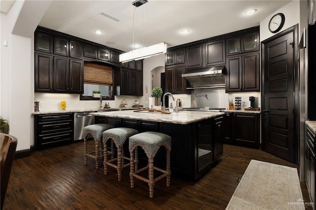 kitchen with sink, stainless steel appliances, hanging light fixtures, dark hardwood / wood-style flooring, and a center island with sink