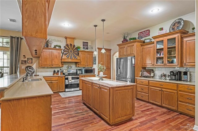 kitchen featuring pendant lighting, hardwood / wood-style flooring, kitchen peninsula, and appliances with stainless steel finishes