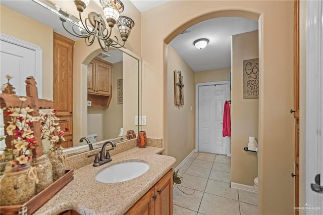 bathroom featuring tile patterned flooring, vanity, an inviting chandelier, and toilet