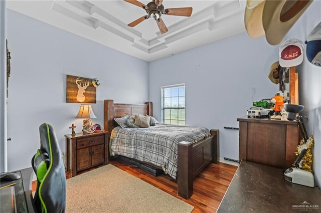 bedroom featuring ceiling fan, dark hardwood / wood-style flooring, and a tray ceiling