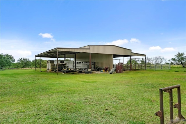 rear view of property with a lawn, a rural view, and an outbuilding