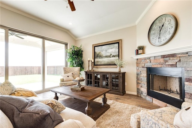 living room with a stone fireplace, light wood-type flooring, ornamental molding, and vaulted ceiling