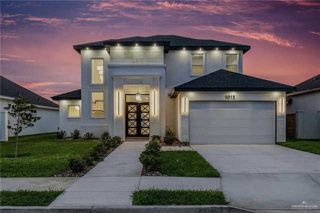 view of front of property featuring a garage, a front yard, driveway, stucco siding, and roof with shingles