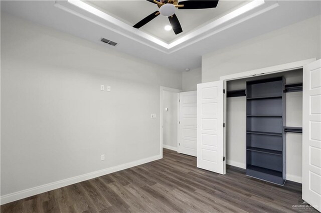 1013 N Buxton Ave, Edinburg, TX 78541 - unfurnished bedroom with a tray ceiling, dark wood-style flooring, baseboards, a ceiling fan, and a closet