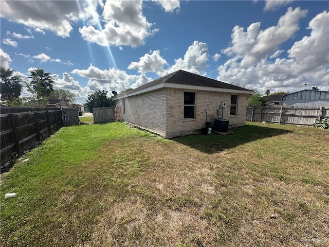 rear view of property featuring a lawn and central air condition unit