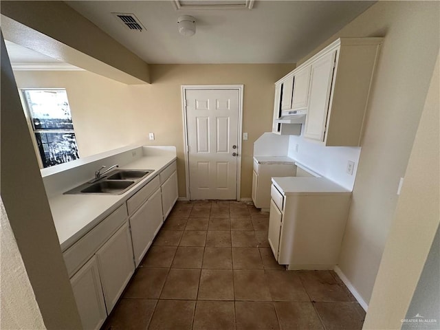 kitchen with dark tile patterned flooring, white cabinetry, sink, and ornamental molding