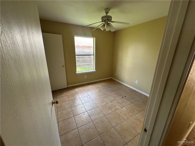 tiled spare room with ceiling fan